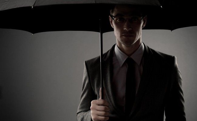 Businessman in costume holding black umbrella
